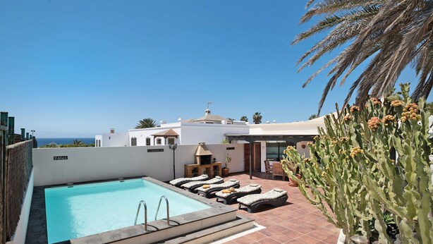 A rooftop pool with lounge chairs, a cactus plant, and a view of the ocean. - Holiday Home "Villa Mar" close to the Beach with Sea View, Pool & Wi-Fi (Teguise)