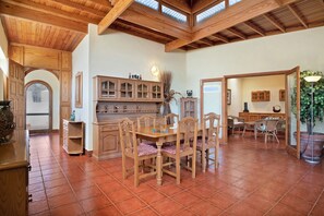 Une salle à manger spacieuse, dotée de meubles en bois et d’un plafond haut.