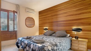 A bedroom with a wooden headboard, a bed with a patterned bedspread, two bedside lamps, and a wooden nightstand with drawers. - Holiday Home "Villa Mar" close to the Beach with Sea View, Pool & Wi-Fi (Teguise)