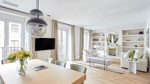 Ett modernt vardagsrum med ett matbord i trä, en soffa, ett soffbord och en öppen spis.