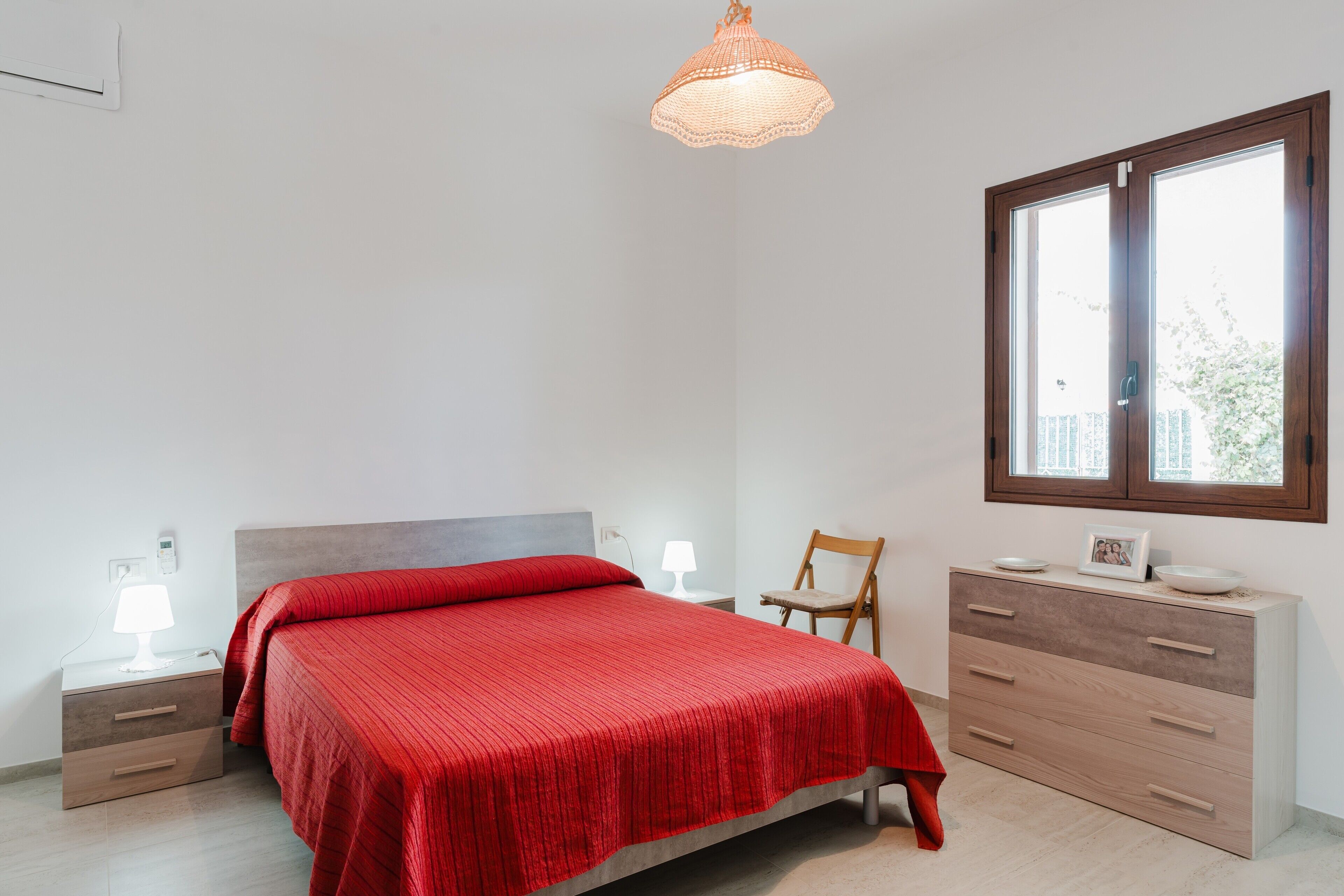 Ein Schlafzimmer mit Bett, Nachttischen, einem Schminktisch und einem Stuhl, sowie einem Fenster.