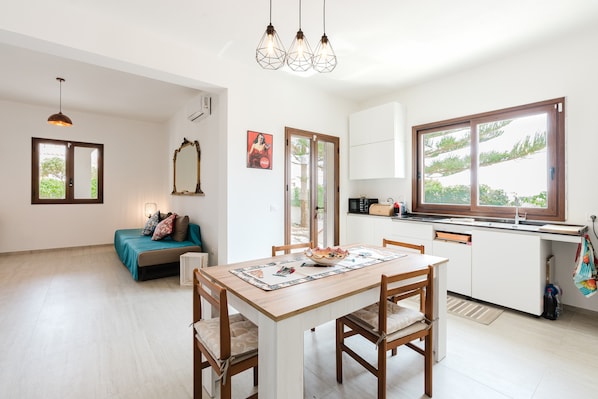 A modern kitchen with a dining table, chairs, and a view through the window.