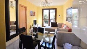 A dining area with a glass table and chairs, a sofa, a TV, and a large mirror. - Holiday Apartment 'Luxury Guesthouse Pula' with Garden, 2 Terraces & Wi-Fi (Pula)