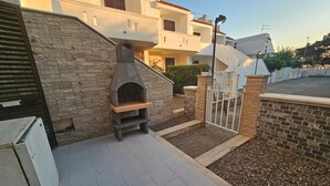 A stone wall, a wooden bench, a paved area, and a gated entrance to a residential complex. - Pet-Friendly 'Villa Andrea' with Sea View, Garden & Wi-Fi (Manduria)