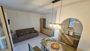 A modern living space with a sofa, dining table, bench, and kitchen area with a hanging light fixture. - Pet-Friendly 'Villa Andrea' with Sea View, Garden & Wi-Fi (Manduria)