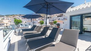 A rooftop terrace with sun loungers, umbrellas, and potted plants. - Spacious apartment in Cómpeta with shared pool and jacuzzi (Cómpeta)