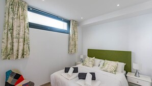 A bedroom with a bed, pillows, a nightstand, a chair, and a window with curtains. - Spacious apartment in Cómpeta with shared pool and jacuzzi (Cómpeta)