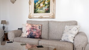 A living room with a sofa, two pillows, a coffee table, a lamp, and a framed painting on the wall. - Apartment 'Sea Views Torre Oceano 7' with Shared Pool & Wi-Fi (Mijas costa)