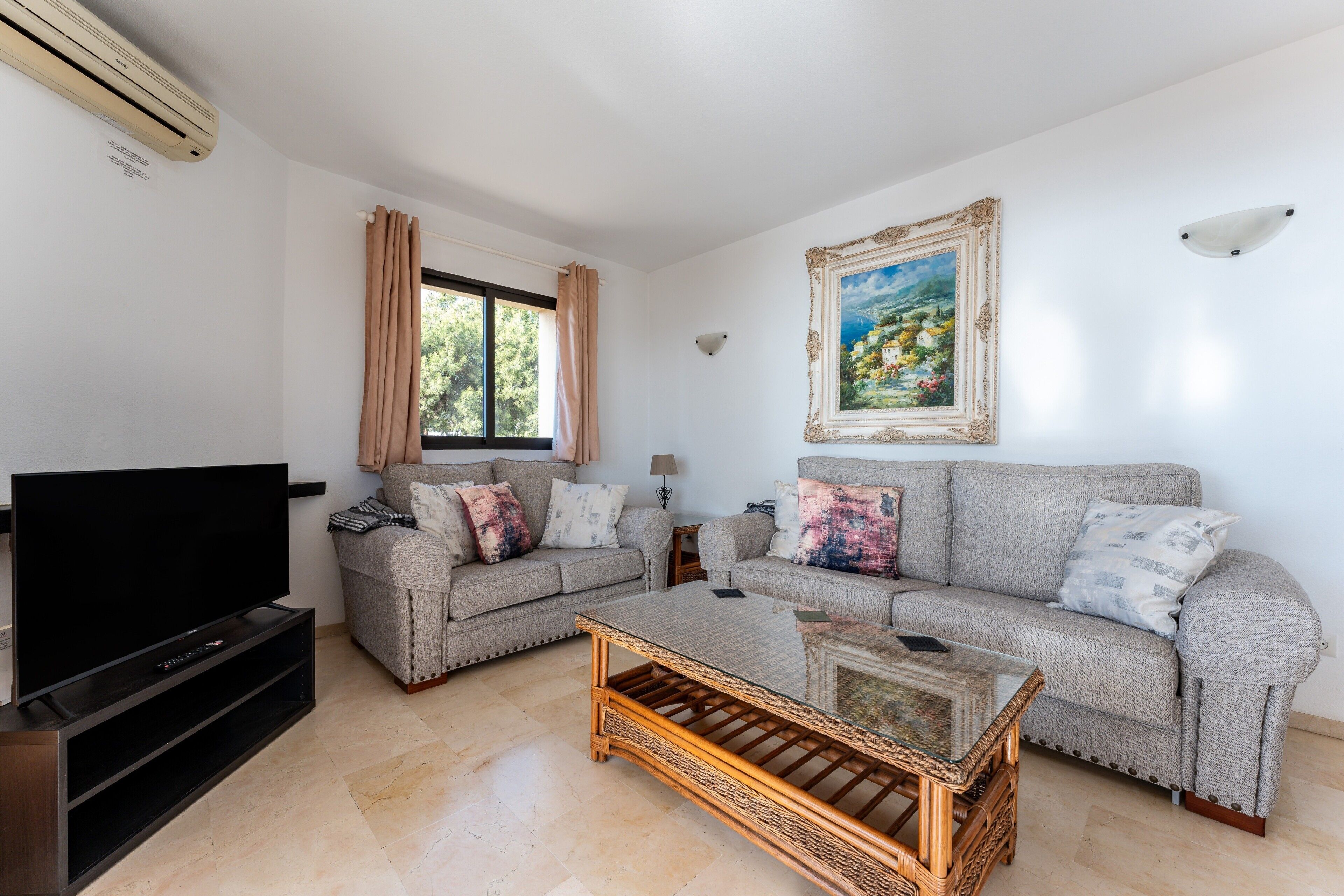 A living room with two sofas, a television, a coffee table, and a painting on the wall.