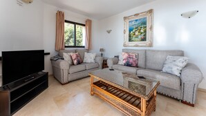 A living room with two sofas, a television, a coffee table, and a painting on the wall. - Apartment 'Sea Views Torre Oceano 7' with Shared Pool & Wi-Fi (Mijas costa)
