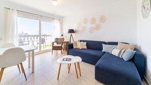 Ein Wohnzimmer mit einer Couch, einem Tisch, einem Sessel und einer Lampe.