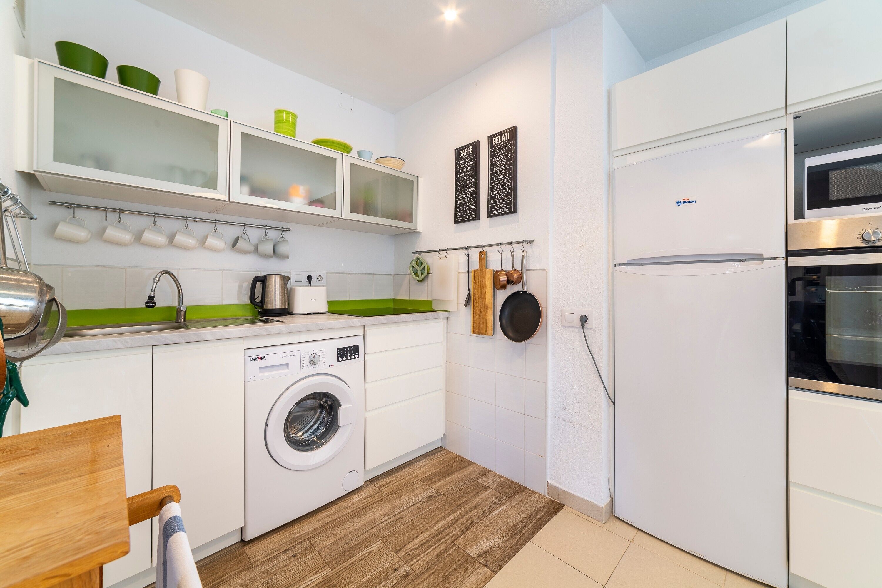 Eine kleine Küche mit Waschmaschine, Kühlschrank und Mikrowelle.