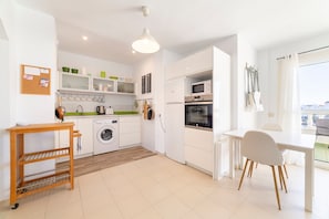 A modern kitchen with a washing machine, microwave, and dining area.
