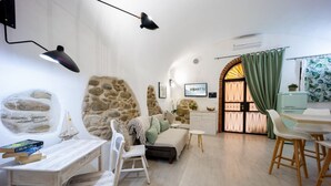 Una sala de estar acogedora con pared de piedra, un sofá, una mesa de comedor y un televisor.