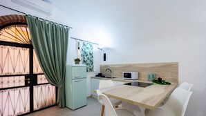 Una cocina compacta con una mesa de madera, sillas blancas, un microondas y un lavabo.