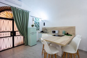 A compact kitchen with a wooden table, white chairs, a microwave, and a sink.