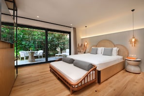 A modern bedroom with a large bed, a wooden bench, and a view of a garden through a sliding glass door.