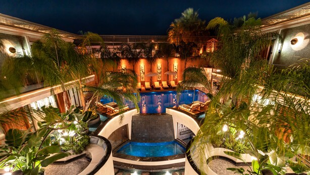 A pool area with lounge chairs, a hot tub, and tropical plants. - Genesis Hotel (Cesme)
