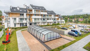 A modern apartment building with multiple balconies, a covered outdoor area, and a parking lot. - Apartamenty Sun & Snow Baltic Sun (Sztutowo)