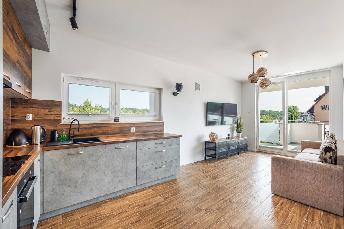 Eine moderne Küche mit einer großen Kochinsel, ein Essbereich mit einer Couch und ein Balkon mit Blick.