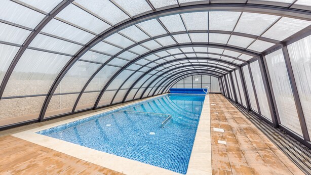 An indoor swimming pool with a glass ceiling and tiled floor. - Apartamenty Sun & Snow Baltic Sun (Sztutowo)