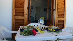 Een eettafel gedekt met borden, een glas en bloemen.