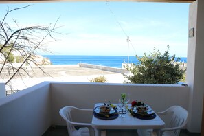 Ein Balkon mit Tisch für Zwei, Blick auf Strand und Meer.