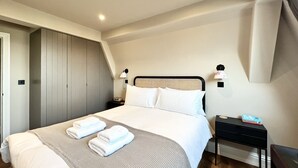A modern hotel room with a large bed, a wardrobe, a nightstand, and a desk. - Redland Suites - Apartment 7 (Redland)