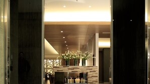 A modern hotel lobby with a glass entrance, a reception desk, and a decorative floral arrangement. - KOKO HOTEL Kobe Sannomiya (Kobe)