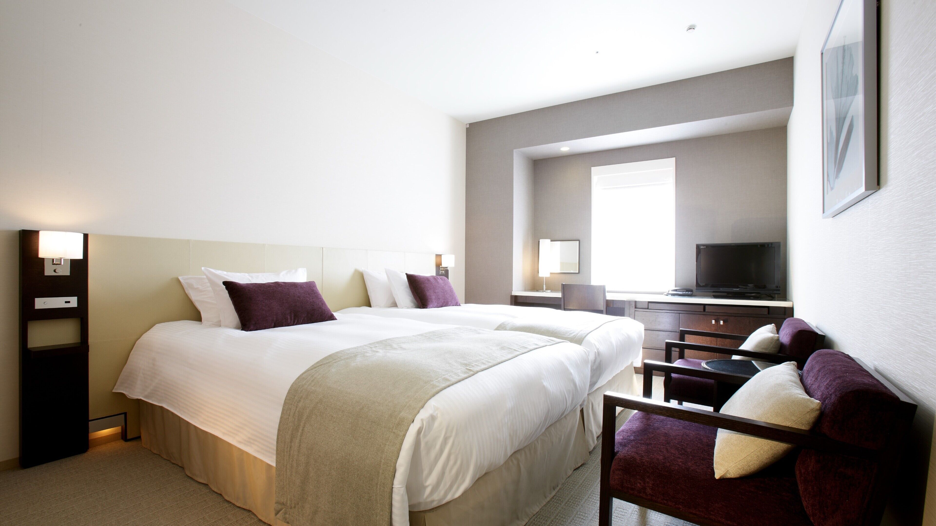 Ein Hotelzimmer mit einem großen Bett, einem Schreibtisch mit Fernseher und einem Sessel.