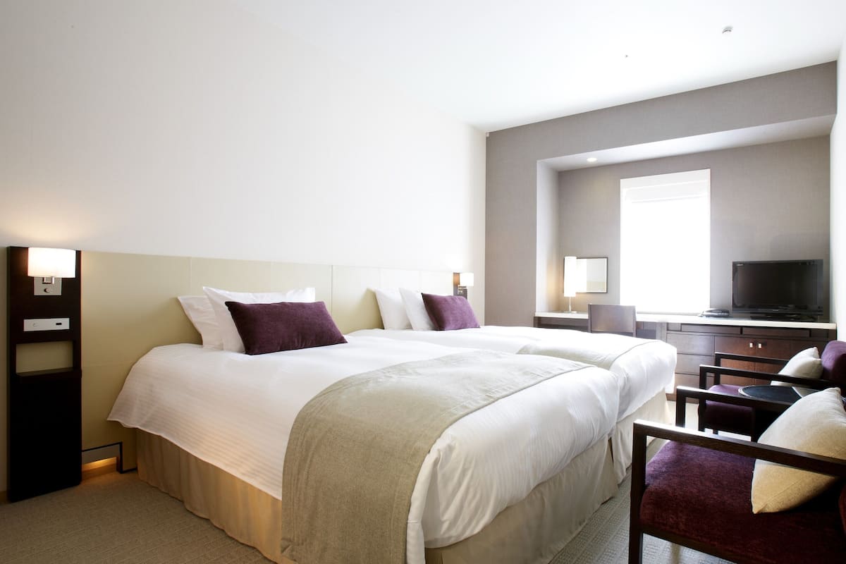 Ein Hotelzimmer mit einem großen Bett, einem Schreibtisch mit Fernseher und einem Sessel.