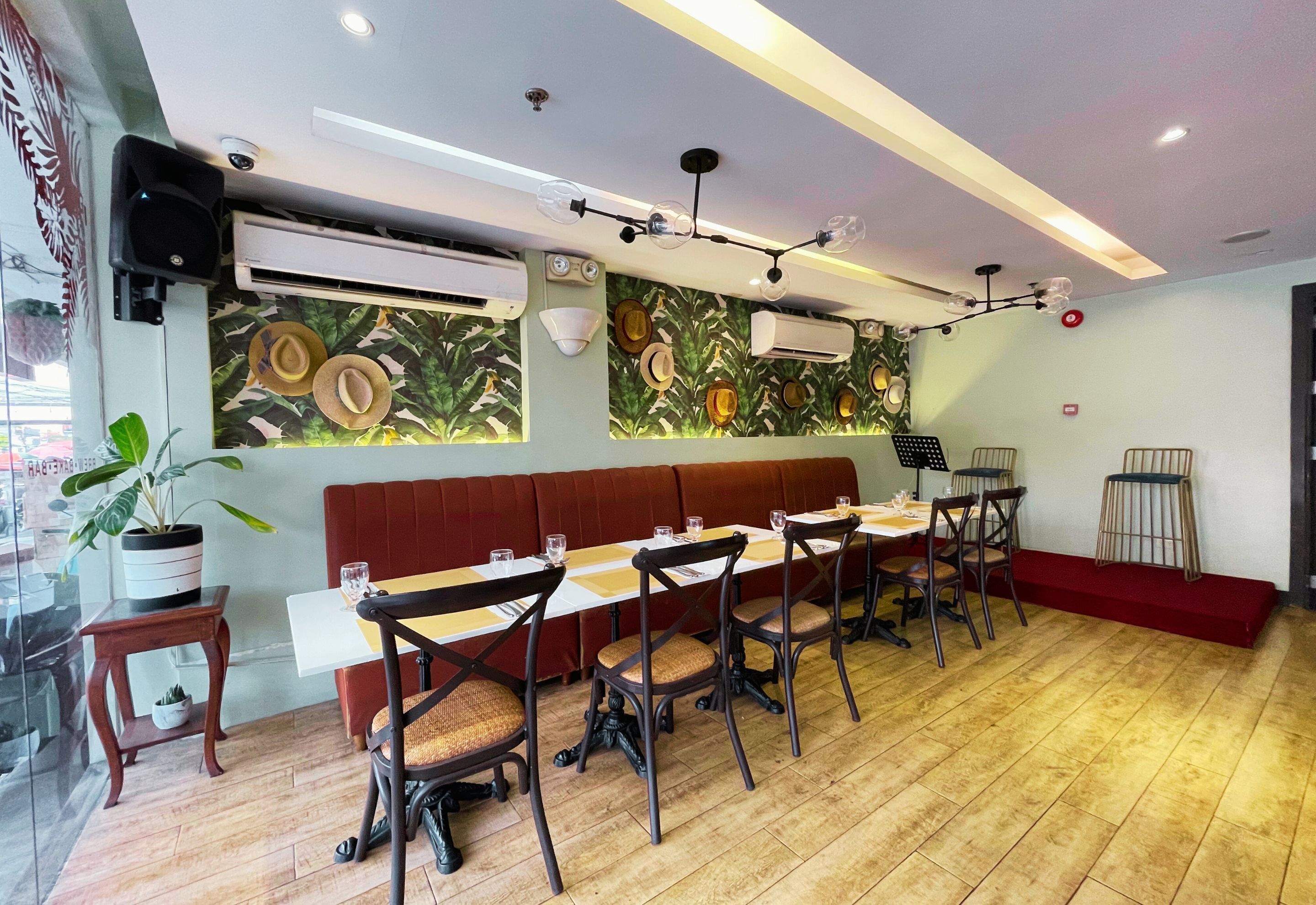 A restaurant with a long wooden table, cushioned chairs, and a red cushioned bench.