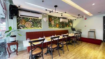 A restaurant with a long wooden table, cushioned chairs, and a red cushioned bench.