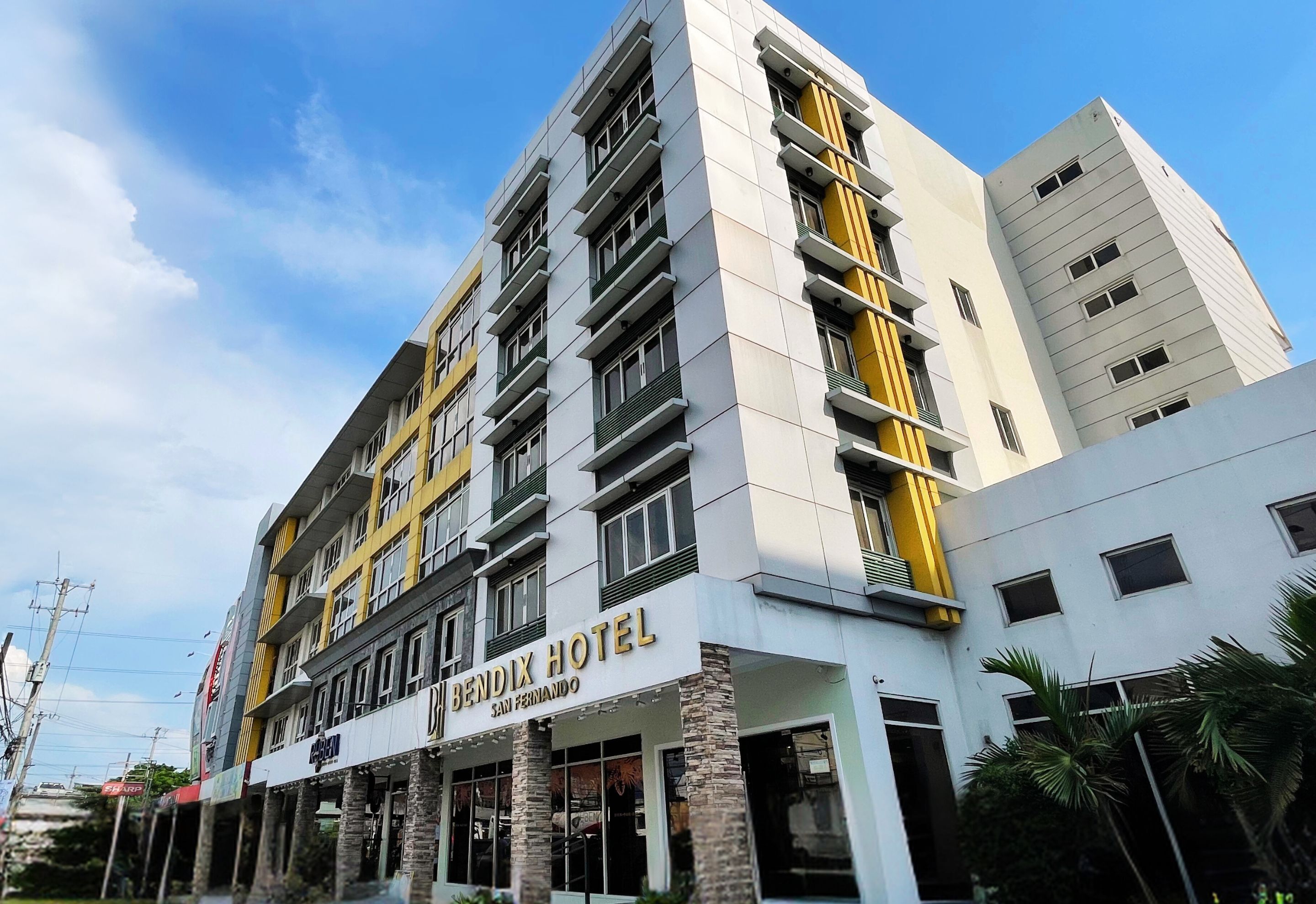 Un hôtel à plusieurs étages, reconnaissable à son enseigne bien visible sur laquelle on peut lire « HÔTEL BENDIX ».
