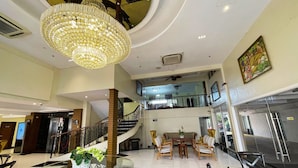 A spacious lobby with a grand chandelier, a central glass table with a plant, and a staircase leading to an upper level. - Bendix Hotel San Fernando powered by Cocotel (San Fernando)