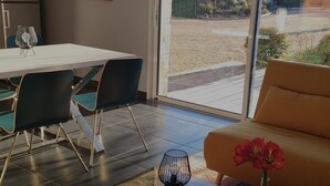Uma sala de estar moderna com área de refeições, janelas amplas e vista para o exterior.