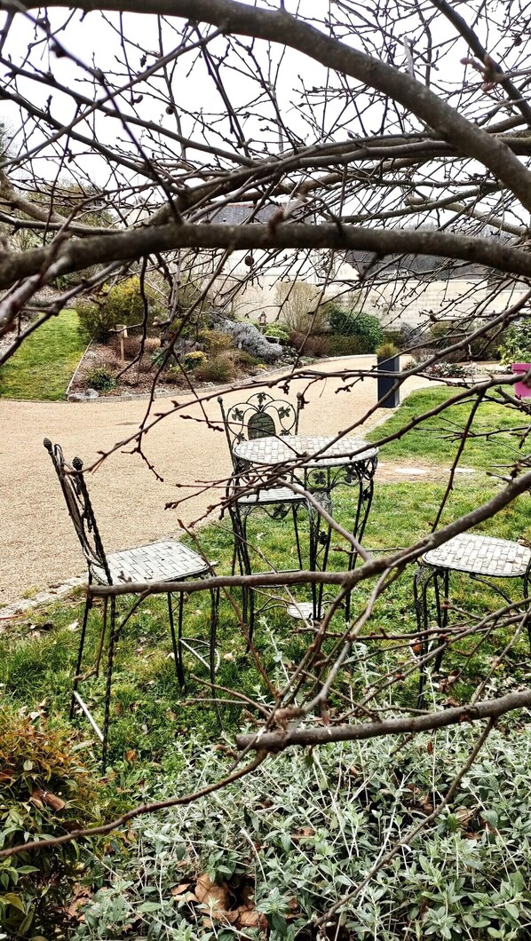 A garden with a metal table and chairs, surrounded by greenery and a gravel path. - Les Logis d Ussé (Rigny-Usse)