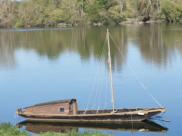 A wooden boat with a cabin and a mast, anchored on calm water with a forested shoreline in the background. - Les Logis d Ussé (Rigny-Usse)