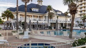 Un resort con piscina, sillas de descanso, sombrillas y un edificio grande con balcones.
