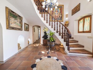 Un magnifique escalier, orné d’un lustre, de tableaux encadrés et d’une plante en pot.