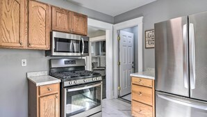 Une cuisine moderne avec des meubles en bois, des appareils électroménagers en acier inoxydable et un plan de travail en marbre.
