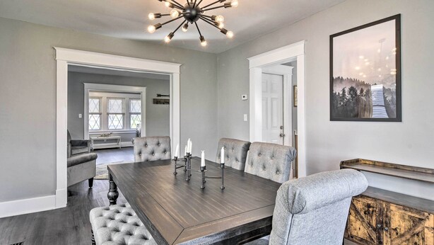 Une salle à manger avec une grande table en bois, des chaises rembourrées et un lustre moderne.