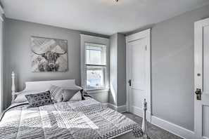 Un dormitorio con cama, ventana, puerta y una obra de arte colgada en la pared.