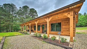 En stuga byggd av trä med en inglasad veranda, omgiven av en grusuppfart och en gräsyta.