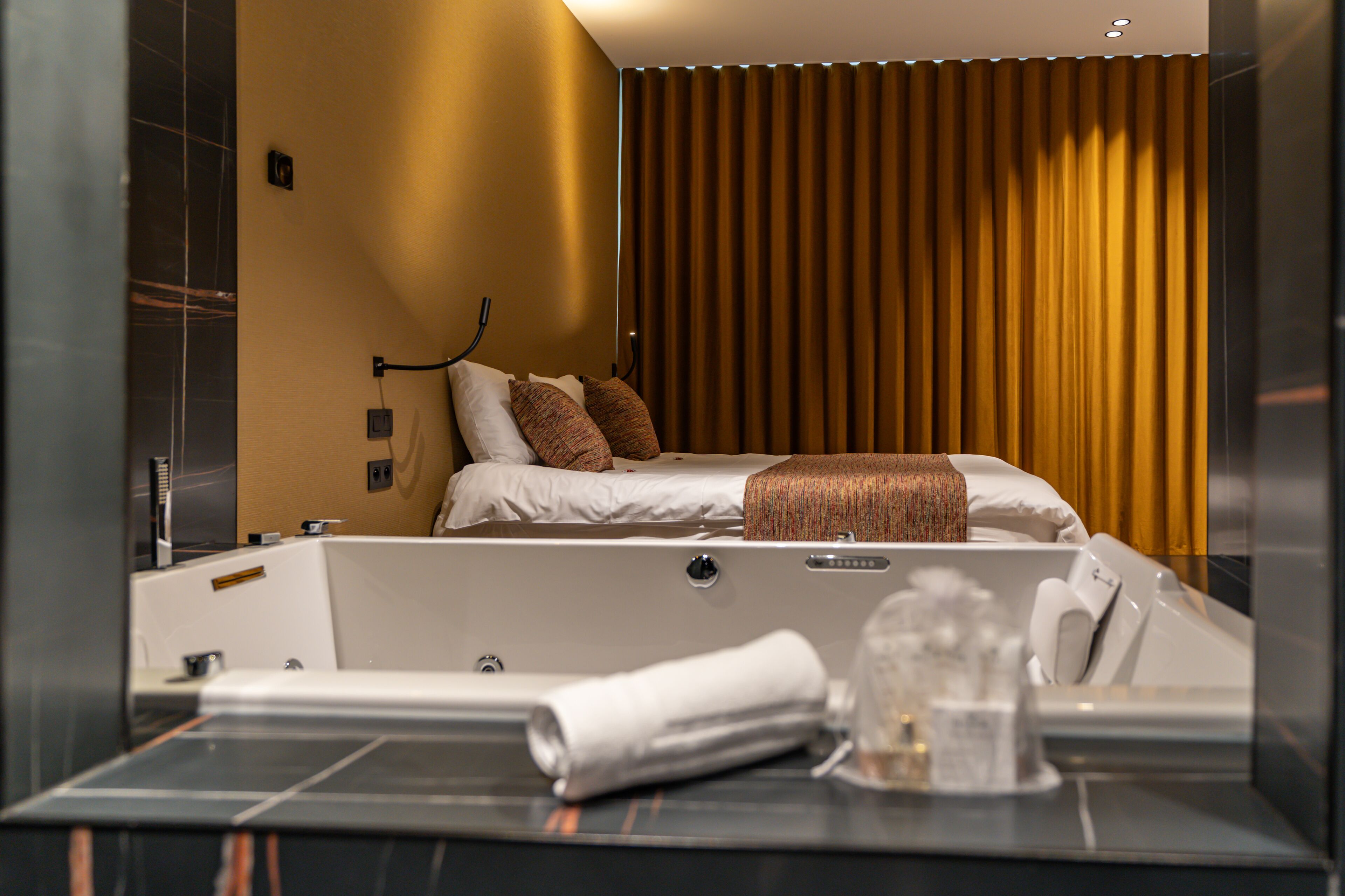 A modern hotel room with a large bed, a separate bathtub, and a large mirror.