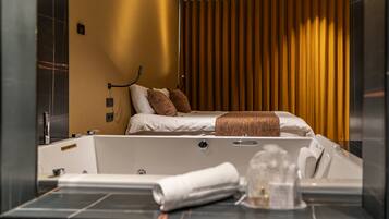 A modern hotel room with a large bed, a separate bathtub, and a large mirror.