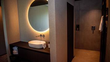 A modern bathroom with a large mirror, a sink, and a shower area.