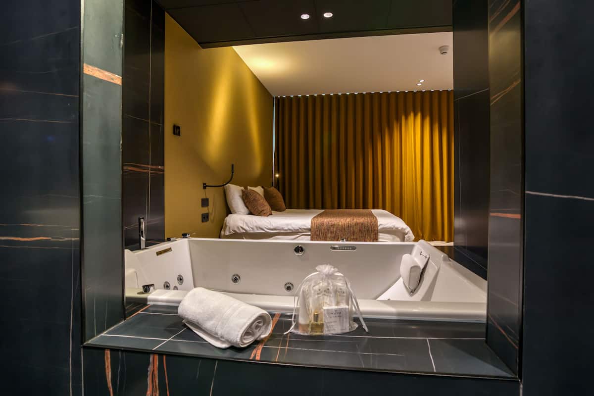 A modern bathroom with a large mirror, a bathtub, and a toilet.