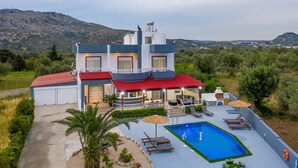 A modern two-story house with a swimming pool, outdoor seating, and a view of the surrounding landscape. - Villa Di Georgia (Αφάντου)