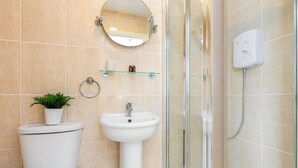 A bathroom with a toilet, sink, shower, and a mirror. -  Cosy studio Apartment near Hyde Park (London)